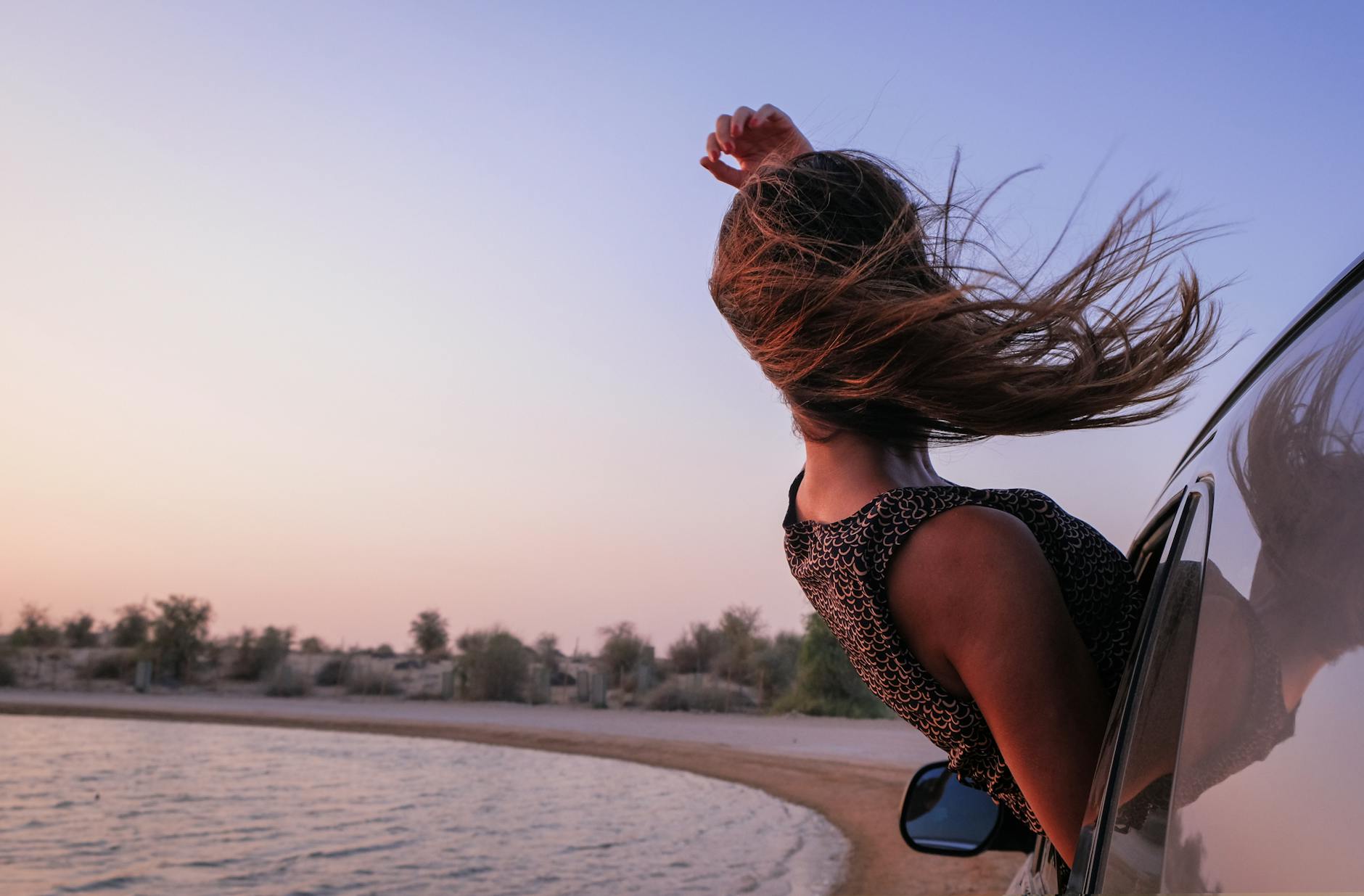 woman with brown hair in car during sunset