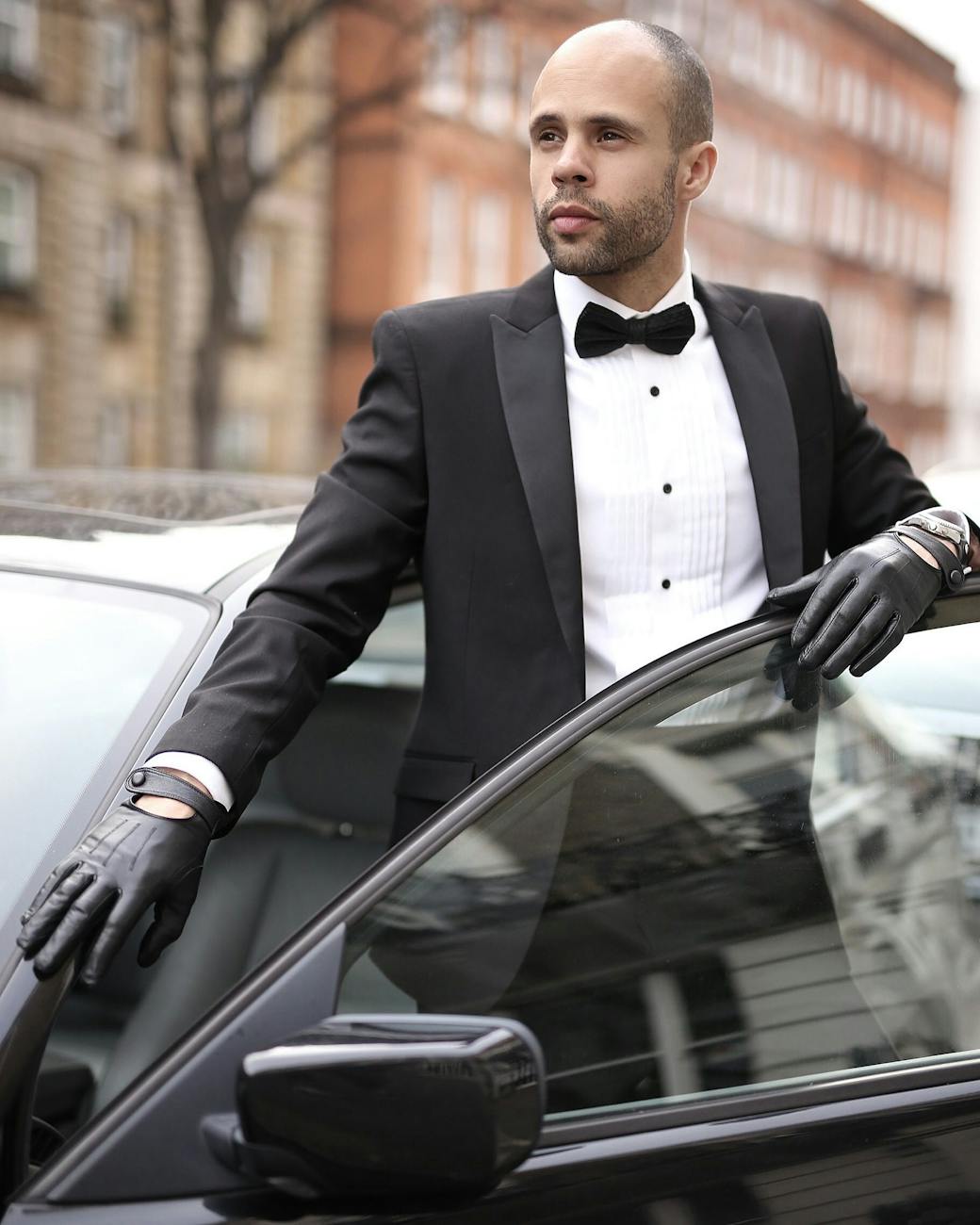 sophisticated man in tuxedo standing by car